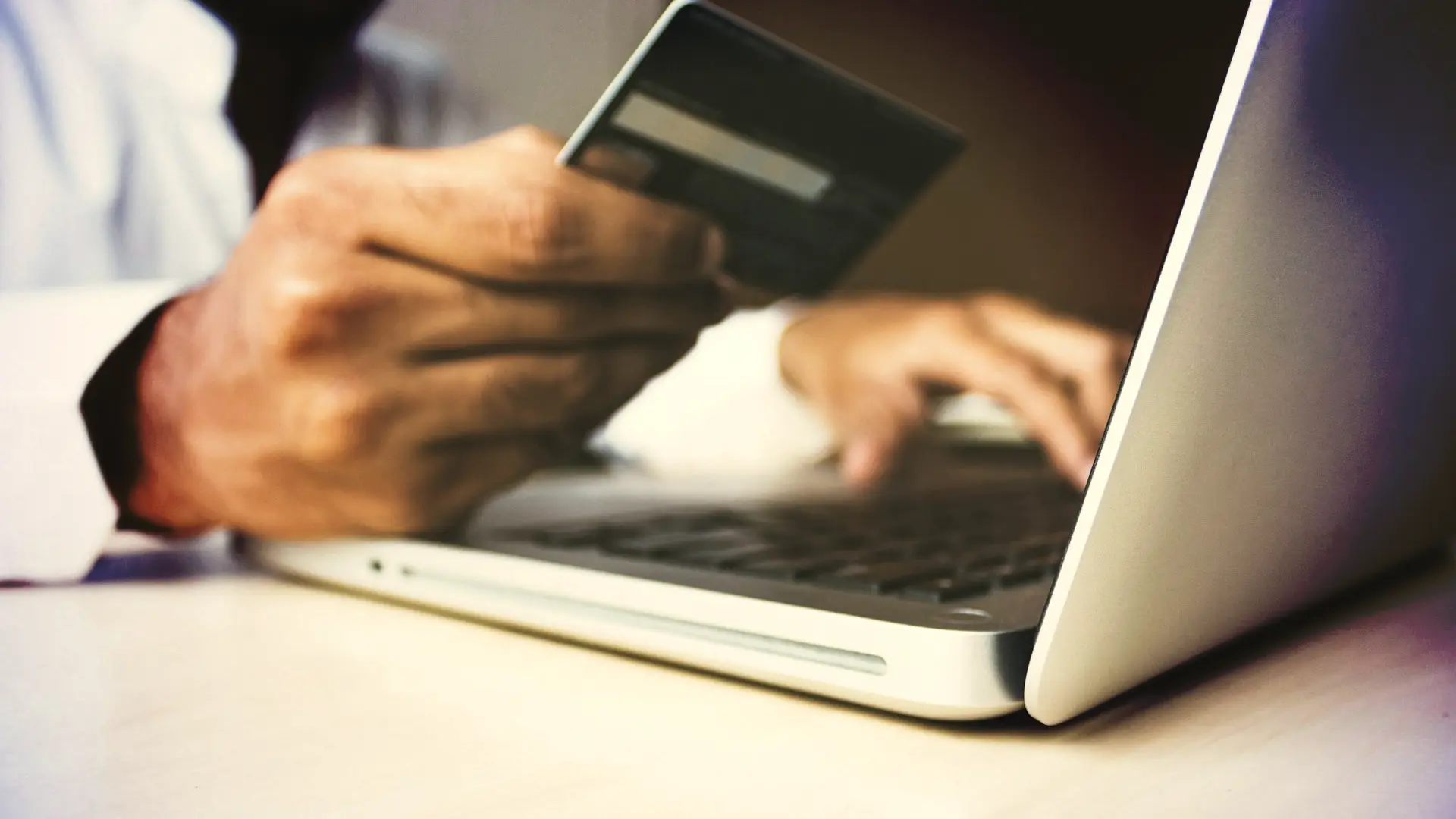 person using laptop computer holding card